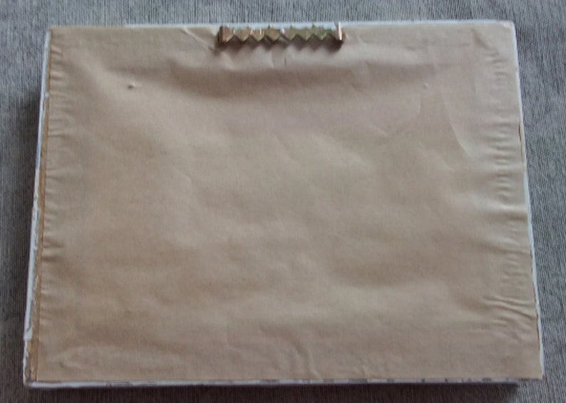 May include: A plain white picture frame with a brown paper backing and a metal hanging hook on the top.