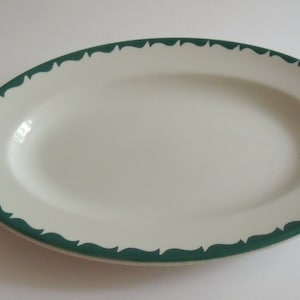 May include: White oval serving platter with a green scalloped border.