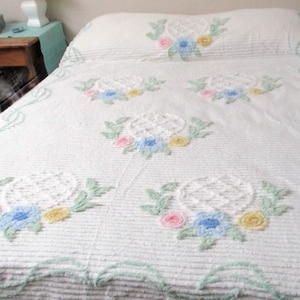May include: White bedspread with embroidered floral designs in pink, blue, and yellow. The bedspread has a striped pattern and a scalloped edge with a light green trim. The pillowcase also features the floral embroidery.