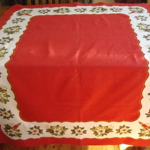 May include: Red tablecloth with a white border featuring a repeating pattern of green leaves, white flowers, and gold ribbon. The border has a scalloped edge.