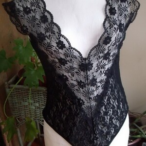 May include: Black lace bodysuit with a deep V-neckline and short sleeves.