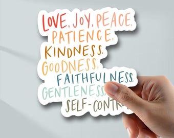 May include: A sticker with the words "LOVE, JOY, PEACE, PATIENCE, KINDNESS, GOODNESS, FAITHFULNESS, GENTLENESS, SELF-CONTROL" in various colors. The sticker is held by a hand against a light gray background.