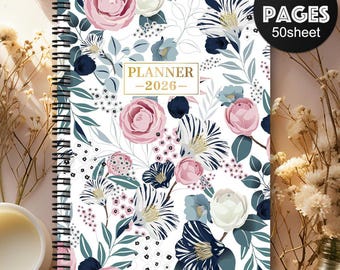 May include: A spiral-bound 2026 planner with a floral design. The cover features pink and white roses, blue and navy flowers, and green leaves on a white background. The planner has 100 pages and the text "PLANNER -2026-" is displayed in gold.