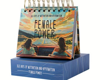 May include: A desk calendar with a spiral binding, featuring the text "FEMALE POWER" and "365 DAYS OF MOTIVATION AND AFFIRMATION." The cover art depicts two women in a vintage car driving on a scenic road. The calendar sits on a blue box.