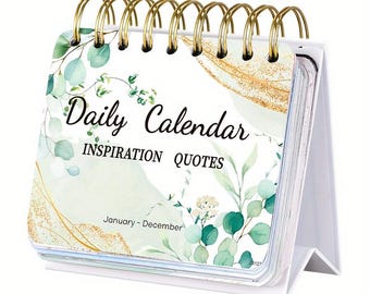 May include: A white desktop calendar with a gold spiral binding. The front cover features a watercolor design of green leaves and gold accents. The text "Daily Calendar Inspiration Quotes" is printed in black. The calendar covers January through December.