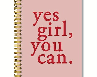 May include: A pink spiral-bound notebook with gold-colored metal rings. The cover features the red text "yes girl, you can."