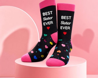 May include: A pair of black crew socks with pink cuffs, heels, and toes. The socks feature the white text BEST Sister EVER and a small red heart. The lower portion of the socks is decorated with a colorful pattern of small hearts in various shades.