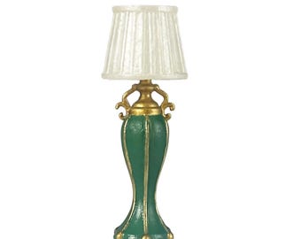 Könnte beinhalten: Eine Miniatur-Tischlampe in Grün und Gold mit weißem Lampenschirm. Die Lampe hat ein detailliertes Design mit goldenen Akzenten und einem plissierten Lampenschirm. Die Lampe ist ein dekorativer Artikel.