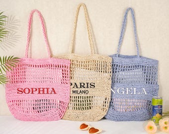 May include: Three open-weave tote bags in pink, beige, and blue. The pink bag has "SOPHIA" embroidered in red. The beige bag has "PARIS MILANO" printed in black. The blue bag has "ANGELA" printed in white.