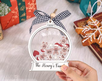 May include: A personalized Christmas ornament with a clear, circular design. Inside are gingerbread people and snowflakes. The ornament has a black and white checkered ribbon and the text "The Henry's Family" and "2025".