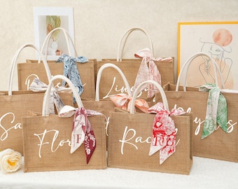 May include: Set of six natural burlap tote bags with white lettering and colorful ribbon accents. The bags are personalized with the names "Sara", "Flora", "Lindsay", "Rachel", "Bridesmaids", and "Yours Truly".