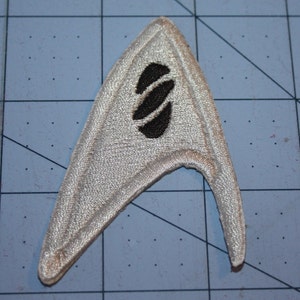 May include: A white embroidered Star Trek insignia patch with a black stylized logo in the center.
