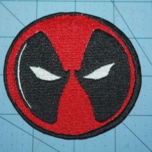 May include: Red and black embroidered patch with a white outline of Deadpool's mask.