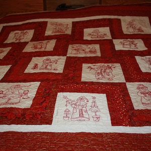 May include: A red and white quilt with a Christmas theme. The quilt is made up of squares with different embroidered designs of Santa Claus and Christmas trees.