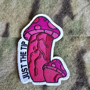 Puede incluir: Parche bordado blanco con un diseño de hongo rosa y el texto "JUST THE TIP".