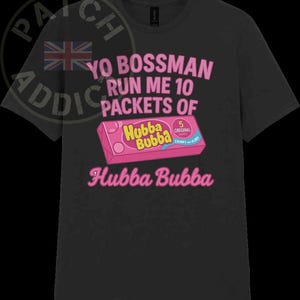 May include: A black t-shirt featuring a pink and white graphic of a Hubba Bubba bubble gum pack. The text on the shirt reads "Yo Bossman Run Me 10 Packets of Hubba Bubba".