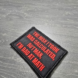 May include: Black embroidered patch with red text that reads "The risk I took was calculated, but man, I'm bad at math."