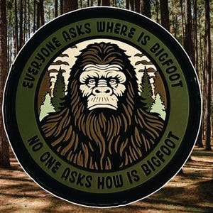 May include: A circular patch with a Bigfoot illustration and the text "EVERYONE ASKS WHERE IS BIGFOOT, NO ONE ASKS HOW IS BIGFOOT". The design uses green and brown tones, a black border, and two pine trees.