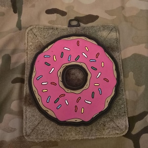 May include: A pink donut with white and colorful sprinkles. The donut is outlined in black and has a brown center.