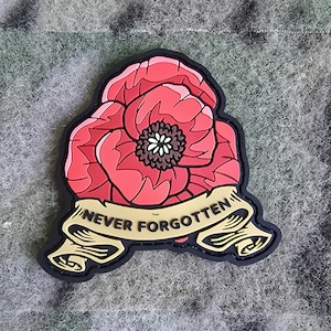 May include: A black and gold embroidered patch with a red poppy flower and the text "NEVER FORGOTTEN".
