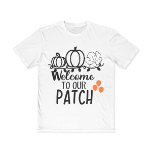 Puede incluir: Camiseta blanca con un gráfico negro de calabazas, hojas y el texto "Welcome to our Patch". Hay tres globos naranjas en el lado derecho del gráfico.