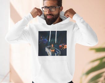 May include: White hooded sweatshirt with a graphic print of a man standing in front of a blue car. The graphic also includes two other men and a red car. The text "Fast" is visible in the graphic.
