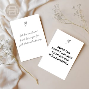 Puede incluir: Dos tarjetas blancas con texto negro y un símbolo de corazón. Una tarjeta dice "Ich bin stark und finde Lösungen für jede Herausforderung." La otra tarjeta dice "JEDER TAG BRINGT MIR NEUE CHANCEN UND MÖGLICHKEITEN."