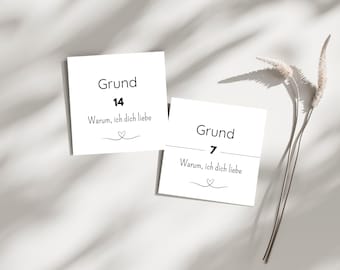 May include: Two white cards with black text and a heart illustration. The cards read "Grund 14 Warum, ich dich liebe" and "Grund 7 Warum, ich dich liebe". Dried ornamental grass is in the background.