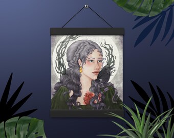 Puede incluir: Una mujer con el pelo largo gris y un cuervo negro posado en su hombro. Lleva un vestido verde y tiene un corazón rojo con una flecha que lo atraviesa en el pecho. El fondo es azul claro con un círculo blanco y una rama de árbol gris oscuro.