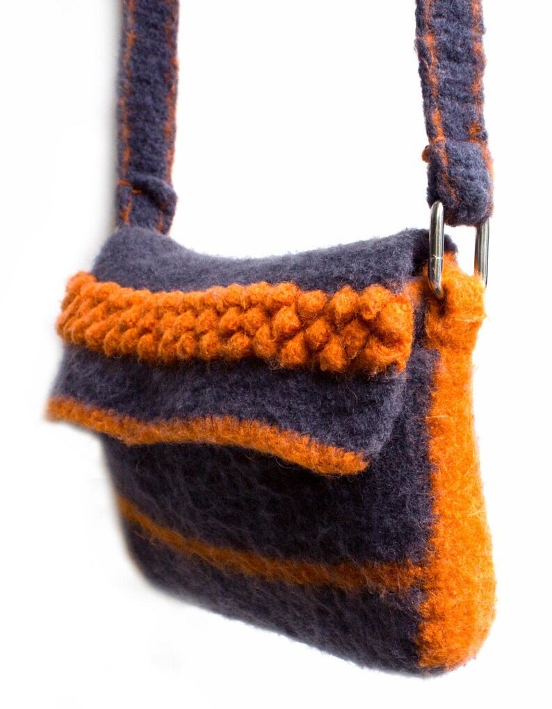 Pu&ograve; includere: Una piccola borsa a tracolla in maglia grigia e arancione con un solo cinturino. La borsa ha una chiusura a lembo e un dettaglio intrecciato sul davanti.