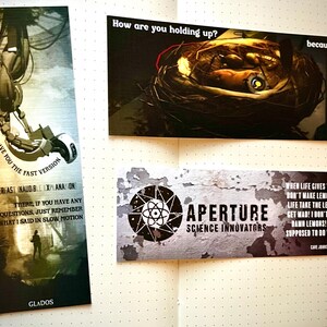 May include: A set of four bookmarks featuring a science fiction theme. The bookmarks feature a robot arm, a potato, a logo for Aperture Science Innovators, and a quote about lemons. The bookmarks are printed on a white background with black text.