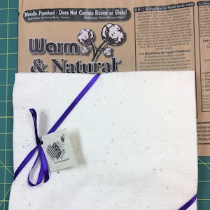 May include: A white needle-punched felt fabric square with a purple ribbon tied around it. The fabric is labeled "Warm & Natural" and says "Needle Punched - Does Not Contain Resins or Glues!"