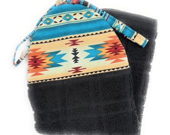 Toalla de cocina/baño reversible con diseño del suroeste de Arizona, en negro, verde azulado, naranja y rojo sobre fondo crema. Se ata para que se mantenga en su lugar.