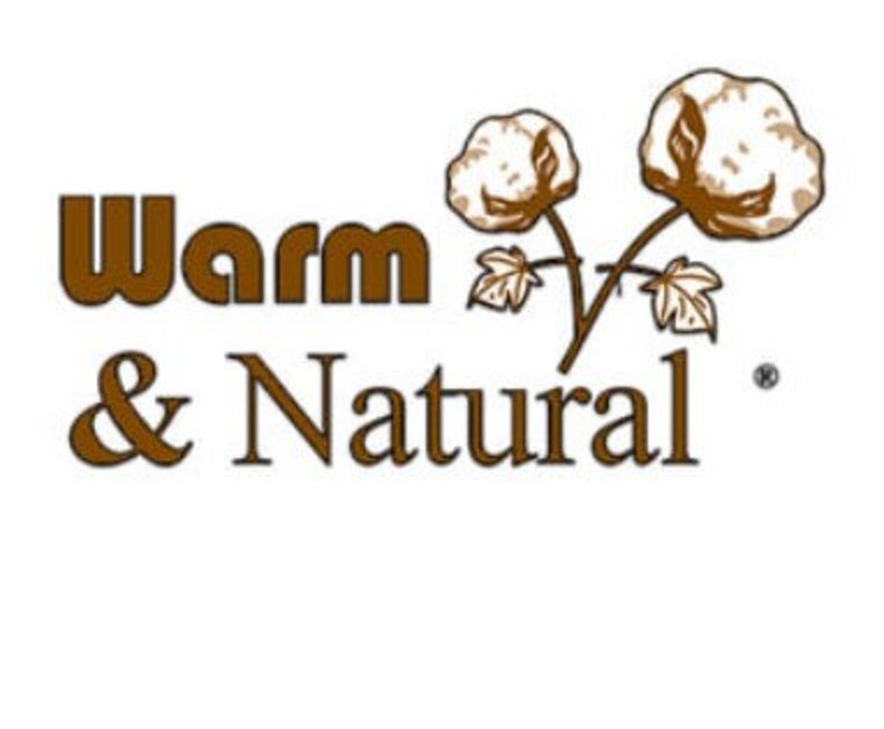 Może przedstawiać: Logo Warm & Natural z brązową czcionką i stylizowanym obrazem dw&oacute;ch kłębk&oacute;w bawełny z zielonymi liśćmi.
