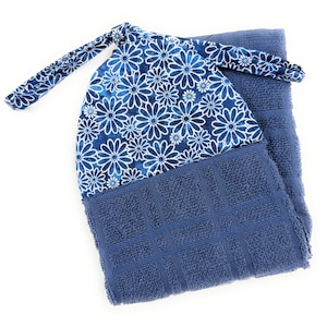 May include: A blue kitchen towel with a floral design on the top portion. The floral pattern features white daisy-like flowers on a dark blue background. The towel has a loop for hanging.