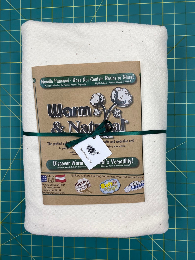 Może przedstawiać: Biała watolina bawełniana z brązową etykietą z napisem "Warm & Natural". Etykieta zawiera napis "Needle Punched - Does Not Contain Resins or Glues!" oraz "Discover Warm & Natural's Versatility!" Etykieta zawiera r&oacute;wnież napis "Made in the USA" i "100% Natural Cotton Fiber Grown in the USA".