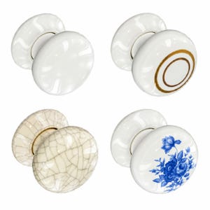 May include: A set of four round ceramic door knobs. One is plain white, one is white with a gold circular ring, one has a cream-colored crackled glaze finish, and one is white with a blue floral pattern featuring roses and leaves.