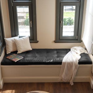 Handcrafted tufted leather cushion styled in a modern living room with neutral tones and plants.