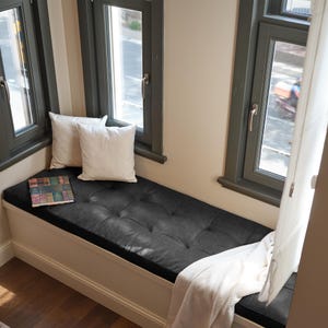 Comfortable leather floor cushion arranged in a cozy reading corner with soft rugs and warm lighting.
