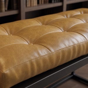 May include: A rectangular bench featuring a tufted tan seat with button detailing. The seat is upholstered in a smooth, textured material and is supported by a sturdy, dark black metal frame with a clean, linear design and a flat base structure.