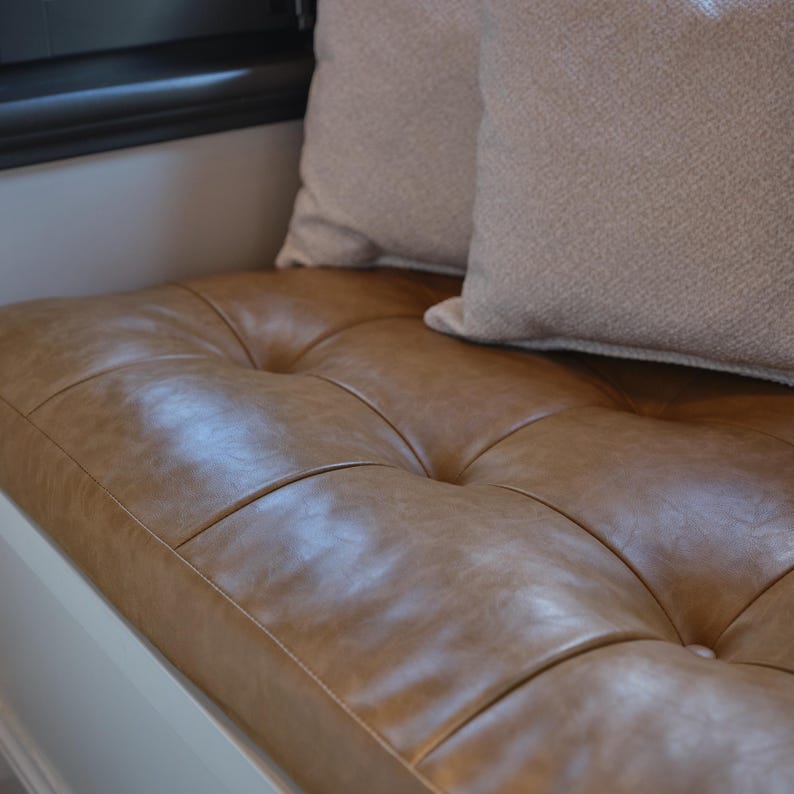 Custom tufted leather cushion displayed on a wooden bench in a modern living room with warm tones.