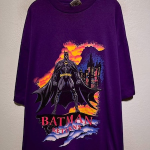 Puede incluir: Camiseta morada de Batman Returns con un gr&aacute;fico de Batman frente a un horizonte urbano con un fondo de puesta de sol. El texto "BATMAN RETURNS" est&aacute; en rosa y blanco.
