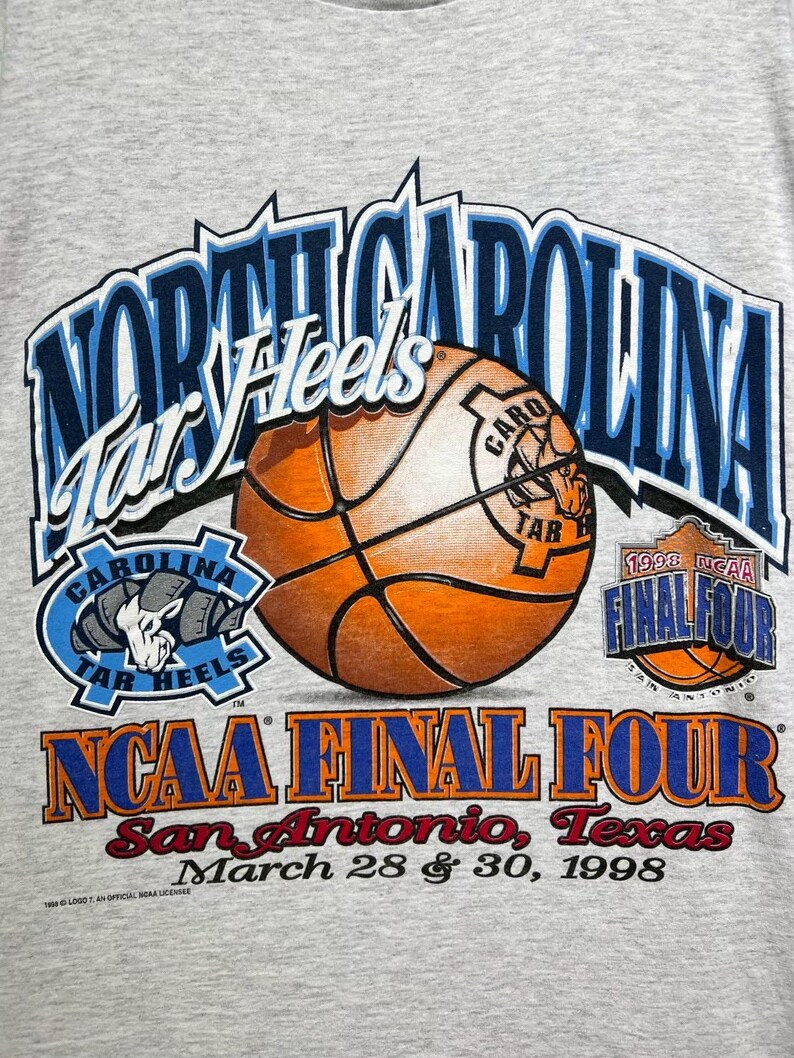 May include: A gray t-shirt featuring the words "North Carolina Tar Heels" in blue and white, along with a basketball graphic. The shirt also displays "NCAA Final Four" and "San Antonio, Texas, March 28 & 30, 1998."