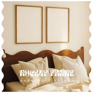 Puede incluir: Dos impresiones artísticas enmarcadas en blanco cuelgan sobre una cama con almohadas y ropa de cama a rayas. Los marcos tienen un acabado dorado. La cama tiene un cabecero de madera oscura. El texto "MOCKUP FRAME psd smart object" es visible.