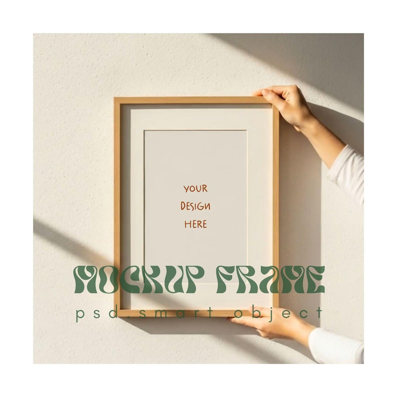 May include: A rectangular wooden picture frame with a white mat, held by a person. The frame has the text "YOUR DESIGN HERE" and "MOCKUP FRAME psd smart object" in green.