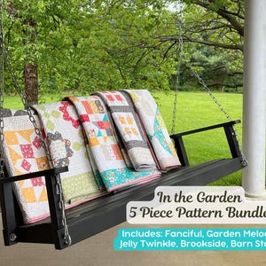 May include: A black wooden porch swing displays five colorful quilts with various patterns. The quilts are in shades of red, yellow, green, and blue. The text "In the Garden 5 Piece Pattern Bundle" is visible, along with the included patterns.