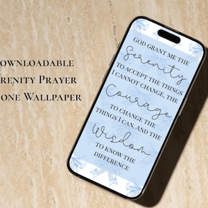 May include: A smartphone displays the Serenity Prayer on a light blue background with floral accents. The phone is angled on a beige surface, with the words "Downloadable Serenity Prayer Phone Wallpaper" in the upper left corner.