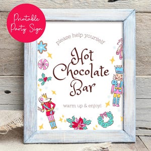 May include: A framed sign with a light blue wooden frame. The sign reads "Hot Chocolate Bar" with decorative illustrations of a nutcracker, mouse, and sweets. The text "Printable Party Sign" is in a pink circle.