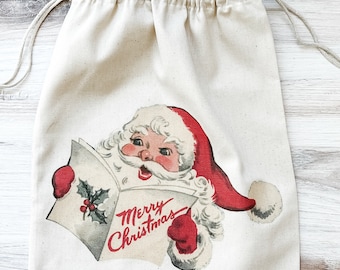 May include: A white cotton drawstring bag with a vintage illustration of Santa Claus holding a card that says "Merry Christmas".