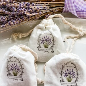 May include: Three small white fabric pouches with drawstrings. Each pouch has a printed design of lavender flowers with the text "Lavender" and "Herbes de Provence".